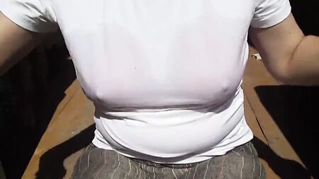 Una ragazza si toglie il reggiseno da bagno bagnato sotto la maglietta bagnata