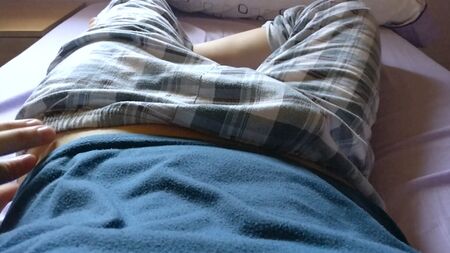 Un ragazzo carino e giovane ci mostra il suo pisello sotto i pantaloni a quadri del pigiama