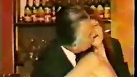 Uomini maturi in giacca e cravatta vengono stuzzicati da una barista matura in tweed