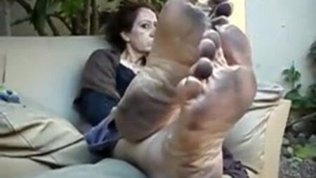 Una donna anziana che mostra i suoi piedi sporchi