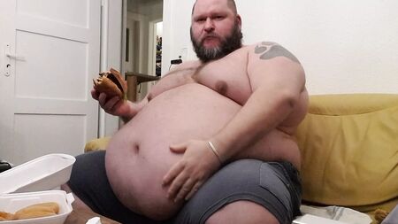 Superchubby SOC - un ragazzo in sovrappeso che mangia un hamburger gigante e anelli di cipolla