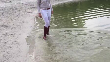 Camminando nel lago con gli stivali da equitazione marroni immersi nell'acqua
